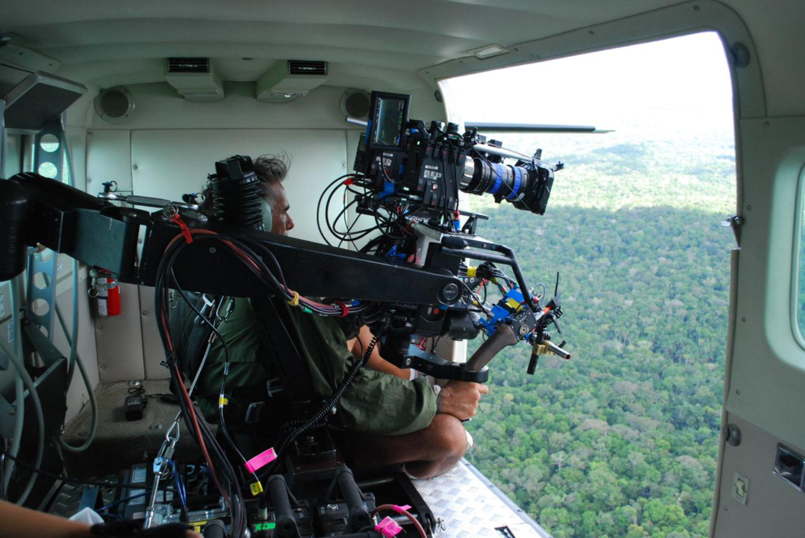 A Brazil Production Services cameraman shoots an aerial view of the jungle with the door of a 9-seater caravan plane open somewhere above the Amazon Rainforest.
