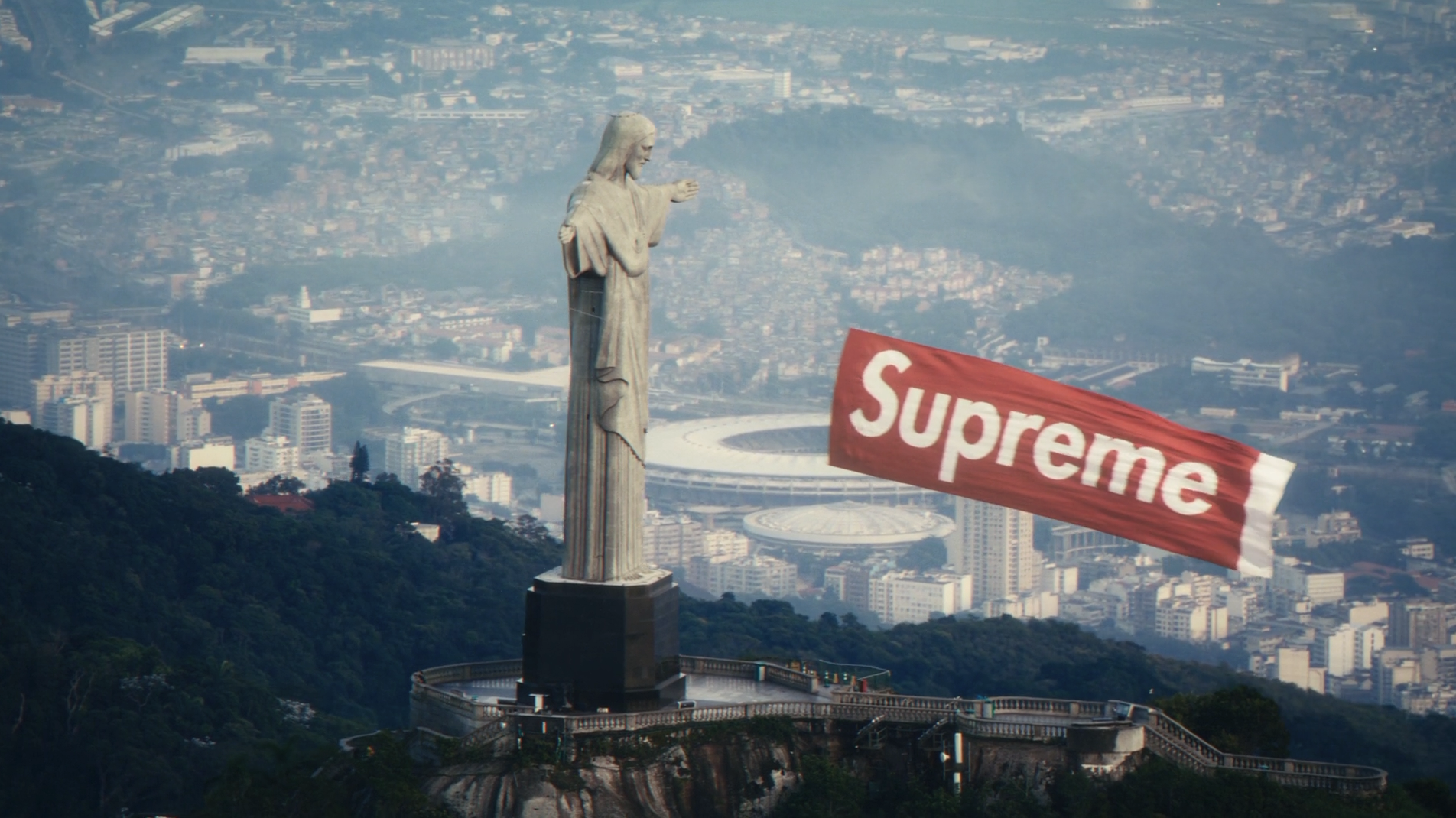 Aerial view of Rio de Janeiro's Christ the Redeemer statue with a Supreme logo overlay, from the brand's commercial shoot