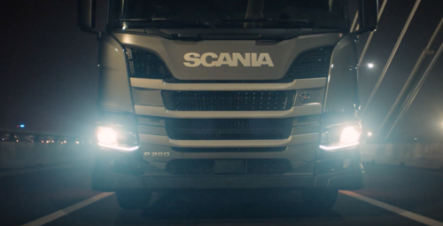 Imagem da frente de um Scania com luzes de xenom acessas