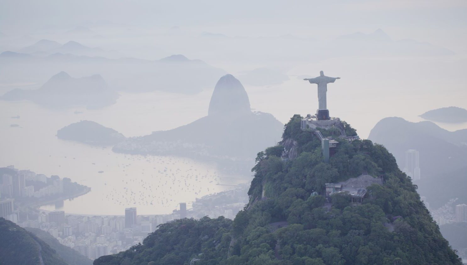 Aerial drone view of Christ the Redeemer statue overlooking Rio de Janeiro's Guanabara Bay at dusk