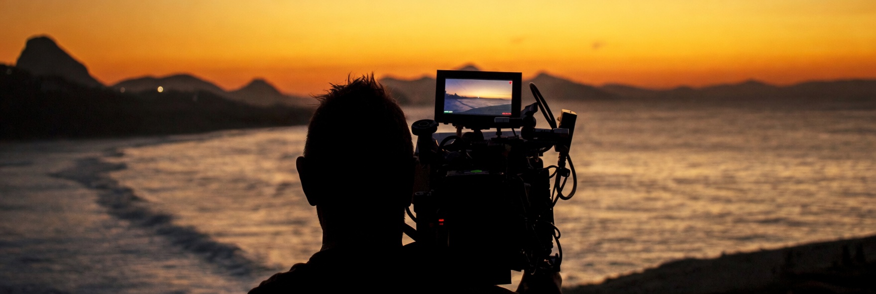 Silhouette of a cameraman filming a sunset over the ocean